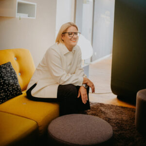 Unternehmerin Swaantje-Verena Hinrichs-Stark sitzt erwartungsvoll auf einem Sofa in einer angenehmen Atmosphäre